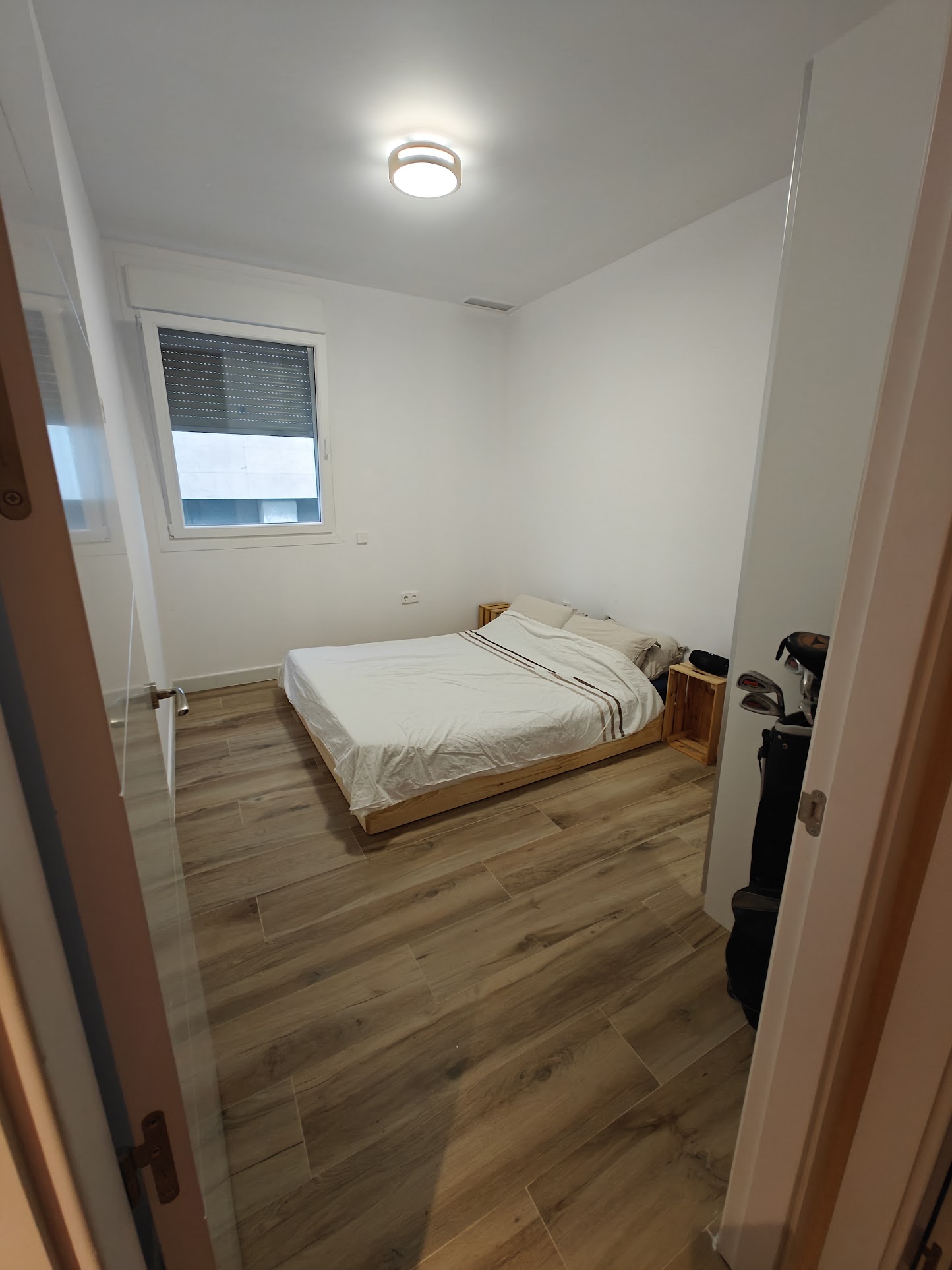 Photo of a bare but tidy bedroom, with a double bed and a wardrobe almost out of shot